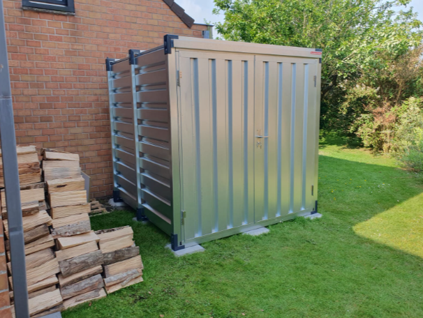 Demontabele opslagcontainer geplaatst in een tuin naast een woning